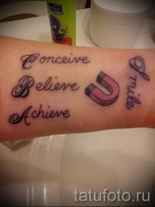 Фото тату на руке с надписью "Conceive, Believe, Achieve" и изображением подковы.