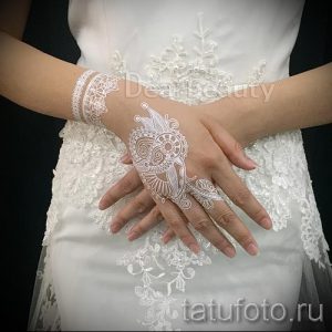 Фото тату хной на руке: кружевной узор, украшающий кисть и предплечье, выполненный в белом цвете. Идеально для свадебного образа.