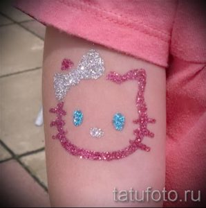 Фото тату Hello Kitty с блестками на руке. Нежный рисунок татуировки для девочек, выполненный в розовых и серебристых тонах.