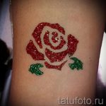 Фото тату на руке: красная роза, выполненная с использованием глиттера. Яркий и привлекательный рисунок татуировки.