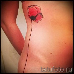 Фото минималистичной татуировки мака на боку. Тонкие линии, красный цветок, длинный стебель, изящный дизайн.