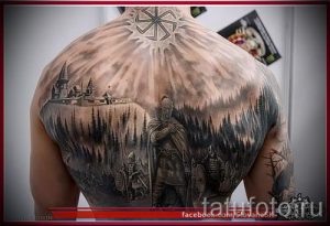 Фотография масштабной татуировки на спине, изображающей славянский пейзаж с замком, лесом и воинами. В верхней части тату изображен символ Коловрат.