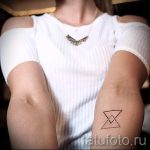 Фото минималистичной татуировки: тонкие черные линии образуют треугольник на предплечье девушки. Простой и стильный рисунок татуировки.