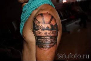 Фото тату на плече: морской закат, волны, скалы. Черно-белая татуировка, реалистичная проработка, морская тематика. Идеи для тату.