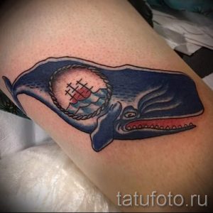 Фото тату: классическая татуировка кита с изображением якоря в круге, выполненная в стиле олд скул на икре.