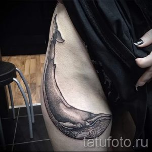 Фото тату: изящный рисунок кита на бедре, выполненный в черно-белой графике с использованием плавных линий и точечной техники.