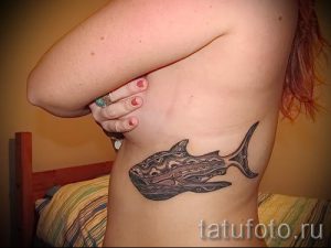 Фото тату: стилизованный рисунок головы кита на боку, выполненный в черно-белой графике с использованием геометрических узоров.