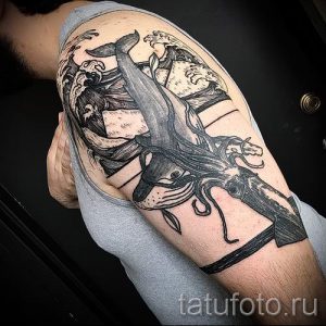 Фото тату: масштабная татуировка на плече с изображением кита, сражающегося с осьминогом. Японский стиль с волнами и детальной проработкой.