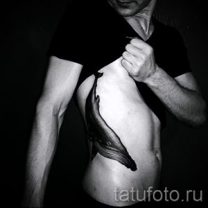 Фото тату: стильная черно-белая татуировка кита, расположенная на боку. Реалистичные детали и плавные линии.