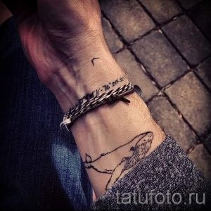 Фото тату на запястье: рисунок кита и географических координат, выполненный в технике лайнарт. Оригинальный и личный дизайн.