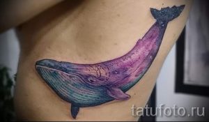Фото тату: акварельный рисунок кита на боку, переливающийся оттенками фиолетового и голубого. Изящный эскиз татуировки для девушек.