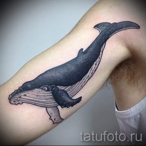 Фото тату: Реалистичная татуировка кита на руке, выполненная в черно-серых тонах. Детализированный рисунок с проработкой текстуры кожи.