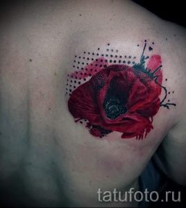 Фото тату акварельного мака на плече, красные и черные оттенки, брызги краски, динамичный стиль, детализированные лепестки.