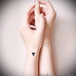 Фото тату: Два треугольника на запястьях, один черный, другой контурный. Минималистичные парные татуировки, символизирующие единство.