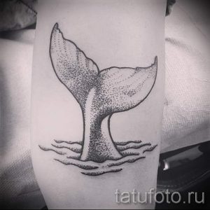 Фото тату: Черно-белая татуировка хвоста кита, выполненная в технике дотворк на предплечье. Детализированный рисунок с волнами.