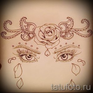 Детальный эскиз татуировки с изображением глаза, украшенного цветами, узорами и бровями. Выполнен в коричневых тонах.