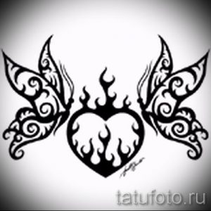 Фото тату: черно-белая татуировка в стиле трайбл с изображением горящего сердца и крыльев. Оригинальный и символичный рисунок.