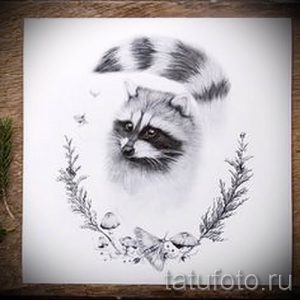 Фото тату реалистичного изображения енота, окруженного грибами и бабочками. Эскиз выполнен в черно-белых тонах с использованием мягких теней.