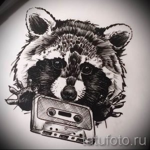Фото тату енота, держащего в лапах кассетный плеер. Черно-белый рисунок татуировки в стиле графика, выполненный опытным мастером.