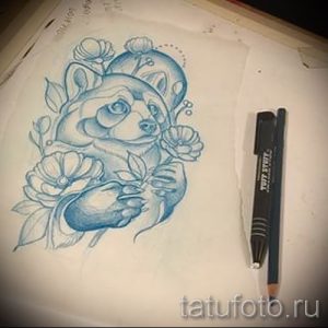 Фото эскиза татуировки енота, окруженного цветами, выполненного в акварельной технике. Нежный и романтичный рисунок.