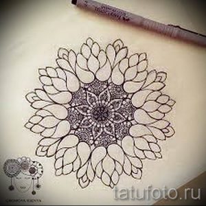Фотография черно-белого эскиза татуировки мандалы с детализированными лепестками и узорами. Подходит для нанесения на спину или плечо, символизирует гармонию и духовность.
