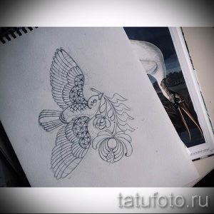 Черно-белый эскиз татуировки, изображающий летящую птицу, окруженную цветами и растительными элементами, выполненный в графическом стиле. Подходит для любителей природы.