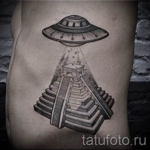 Черно-белая татуировка на боку с изображением НЛО, парящего над древней пирамидой, выполненная в технике дотворк.