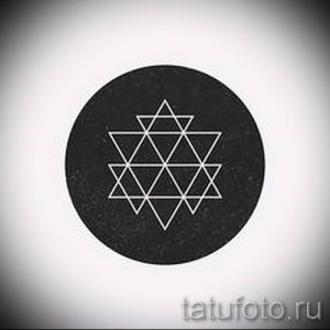 Фото тату: эскиз татуировки, изображающий геометрический узор, заключенный в круг, выполненный тонкими белыми линиями на черном фоне.