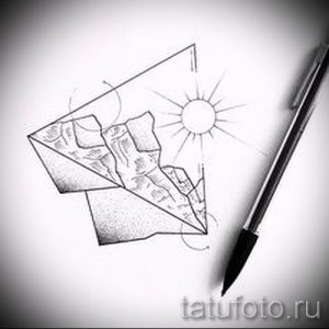Фото тату: эскиз татуировки, изображающий бумажный самолетик, летящий к солнцу, выполненный в технике графики с использованием штриховки.