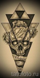 Фотография татуировки в стиле dark realism с изображением черепа, обвитого розами, заключенного в треугольник. Детализированный рисунок с использованием теней и световых эффектов.