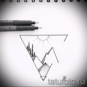 Фотография черно-белой татуировки с изображением горного пейзажа, заключенного в треугольник. Солнце, деревья и горы создают атмосферу спокойствия и умиротворения.
