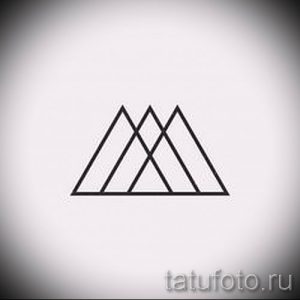 Черно-белое фото минималистичной татуировки с изображением трех пересекающихся треугольников. Простой и стильный рисунок для любителей геометрии.