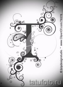 Черно-белое фото тату с буквой 'T', окруженной спиралями, кругами и точками. Оригинальный и необычный дизайн для любителей абстрактных рисунков.