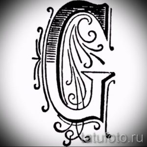 Фото тату: стилизованная буква 'G' с декоративными элементами, выполненная в черном цвете. Подходит для инициалов и монограмм.