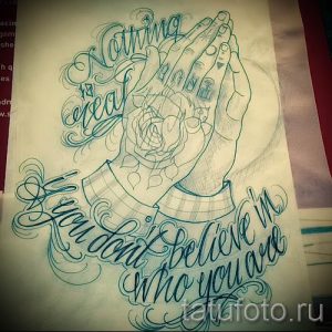 Черно-серый эскиз татуировки, изображающий молящиеся руки, держащие розу. Надпись "Nothing is real. If you don't believe in who you are" обрамляет композицию.