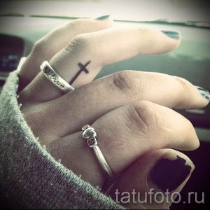 Фотография заслуживающей внимания уже нанесенной на тело татуировки на пальце с крестом для подбора и создания своего эскиза - пример