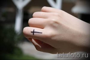 Фото заслуживающей внимания уже нанесенной на тело татуировки на пальце с крестом для подбора и создания своего эскиза - идея