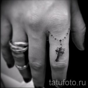 Фотография заслуживающей внимания уже нанесенной на тело тату на пальце с крестом для подбора и создания своего эскиза - пример