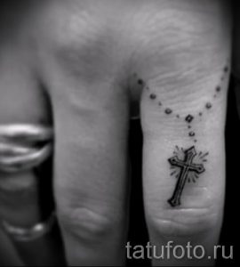 Фотография заслуживающей внимания уже нанесенной на тело татуировки на пальце с крестом для подбора и создания своего эскиза - пример