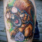 Фото тату разъяренной белки с открытым ртом и надписью 'Nuts'. Яркие цвета и мультяшный стиль.