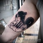 Фото тату белки на руке, выполненной в технике blackwork с изображением леса, гор и луны. Татуировка имеет мистический и загадочный вид.