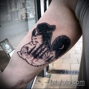Фото тату белки на руке, выполненной в технике blackwork с изображением леса, гор и луны. Татуировка имеет мистический и загадочный вид.