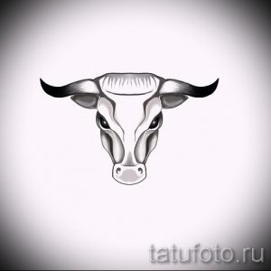 Фото татуировки с изображением головы быка, выполненной в серо-черных тонах. Детализированная проработка шерсти и рогов создает реалистичный и эффектный образ.