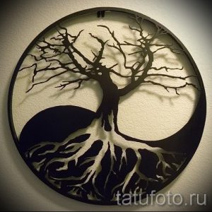 Фото тату Инь и Ян, в котором нижняя часть символа трансформируется в дерево жизни с корнями. Черно-белый рисунок татуировки.