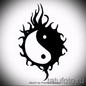Фото татуировки Инь и Ян, окруженной языками пламени. Черно-белый рисунок, символизирующий страсть, трансформацию и борьбу противоположностей.