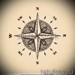 Фото татуировки с изображением старинного компаса в стиле гравюры. Рисунок выполнен в коричневых тонах на бежевом фоне.