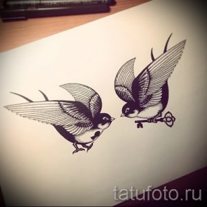 Эскиз татуировки с изображением двух летящих ласточек, одна из которых держит в клюве старинный ключ. Черно-белый рисунок, выполненный точечной техникой.