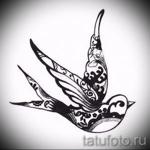 Черно-белый эскиз татуировки ласточки, тело и крылья которой украшены сложным орнаментом.