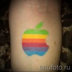 Фото тату: логотип компании Apple, выполненный в цветах радуги, нанесен на руку. Татуировка выглядит ярко и узнаваемо.