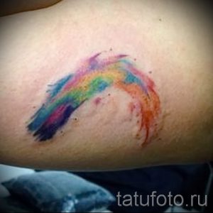 Фото тату: маленькая, красочная радуга, нанесенная на запястье. Использованы яркие, пастельные цвета, создающие эффект акварели.